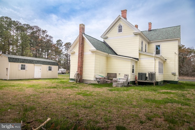 rear view of property featuring a yard, cooling unit, and a storage shed