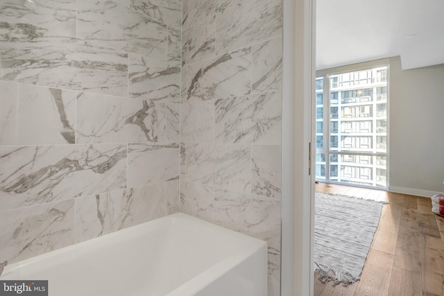 full bath with a bathing tub and wood finished floors