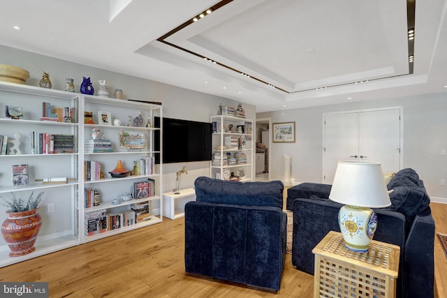 living area with light wood finished floors and a tray ceiling