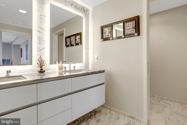 bathroom with marble finish floor, a sink, baseboards, and double vanity