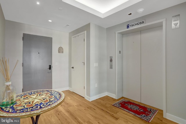 entrance foyer with elevator, baseboards, wood finished floors, and recessed lighting