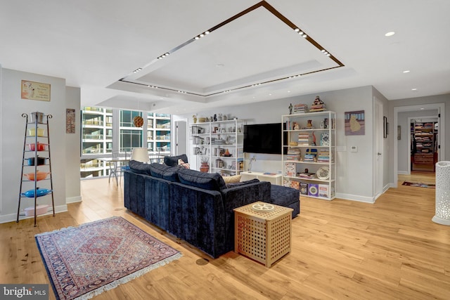 living room with floor to ceiling windows, recessed lighting, a raised ceiling, light wood-style floors, and baseboards