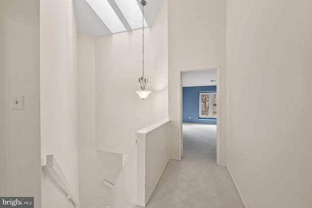 hallway featuring light carpet and a skylight