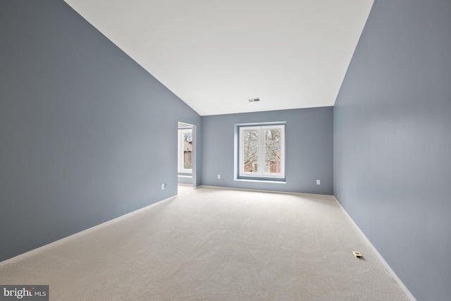 carpeted empty room with high vaulted ceiling