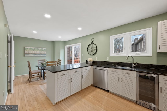 kitchen featuring white cabinetry, sink, beverage cooler, stainless steel dishwasher, and kitchen peninsula