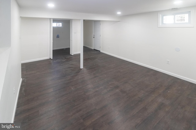 basement featuring plenty of natural light and dark hardwood / wood-style flooring