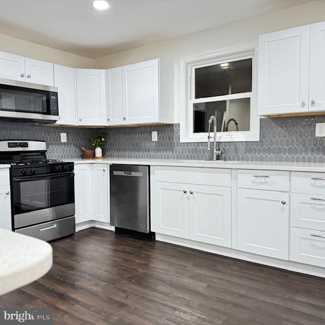 kitchen with appliances with stainless steel finishes, sink, dark wood-type flooring, and white cabinets