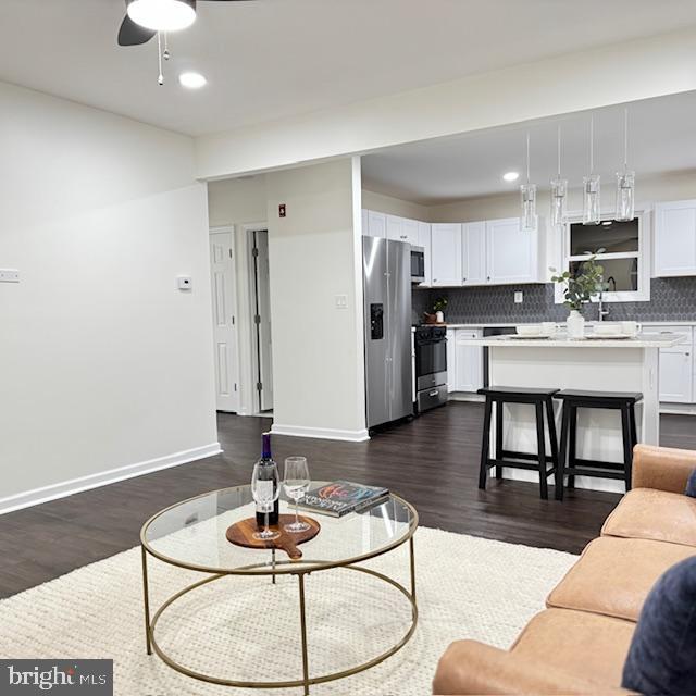 living room with ceiling fan and dark hardwood / wood-style floors