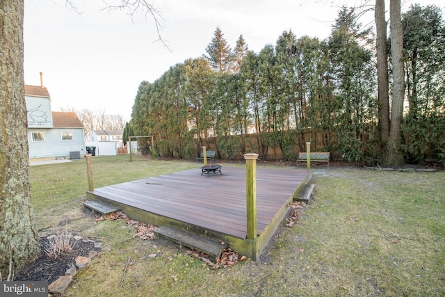 deck with a lawn, a fire pit, and cooling unit