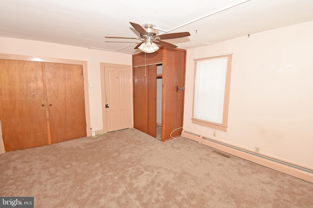 unfurnished bedroom with ceiling fan, multiple closets, a baseboard radiator, and light colored carpet