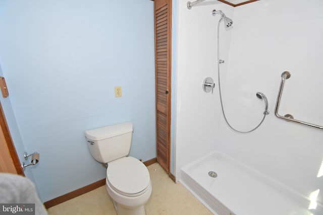 bathroom featuring a closet, a stall shower, toilet, and baseboards