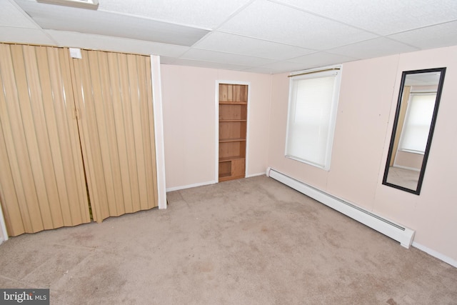 unfurnished bedroom with a baseboard radiator, a drop ceiling, and light colored carpet