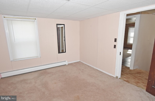 unfurnished room featuring a baseboard heating unit, a drop ceiling, and light carpet