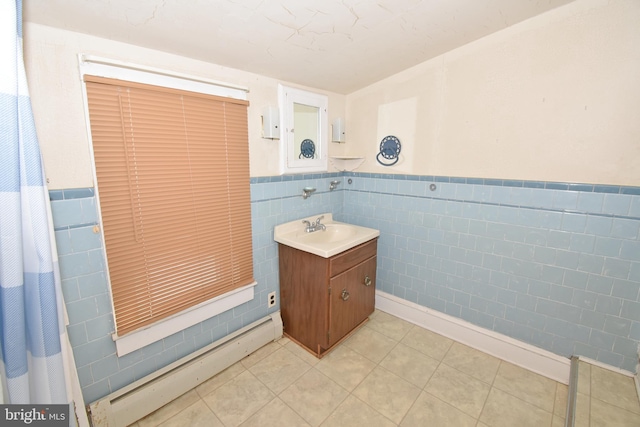 bathroom featuring a baseboard heating unit, tile patterned flooring, vanity, and tile walls