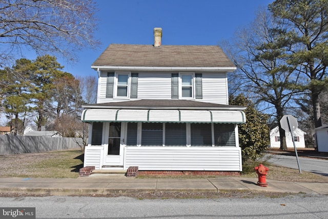 view of front facade featuring a chimney and fence