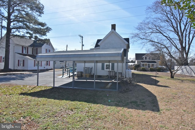 rear view of house featuring a carport and a lawn