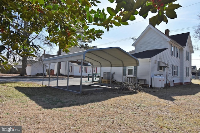 exterior space featuring a chimney, a front lawn, and a carport