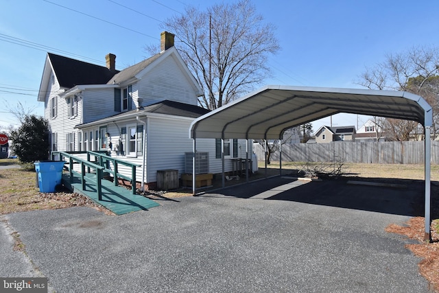 view of parking / parking lot featuring a carport, fence, and aphalt driveway