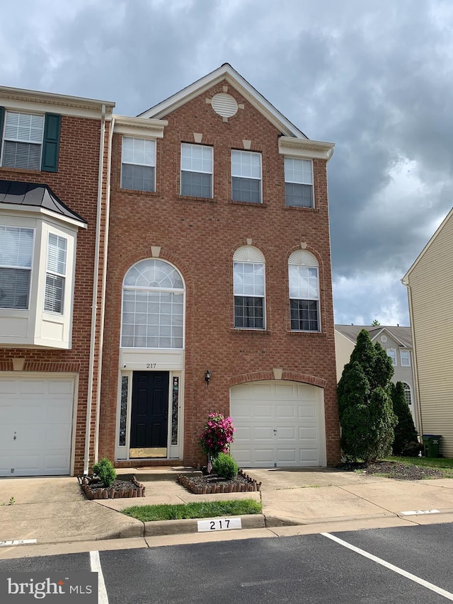 multi unit property featuring a garage, concrete driveway, and brick siding