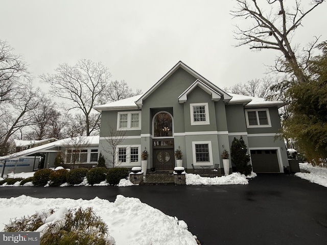 traditional home with aphalt driveway, a garage, and stucco siding