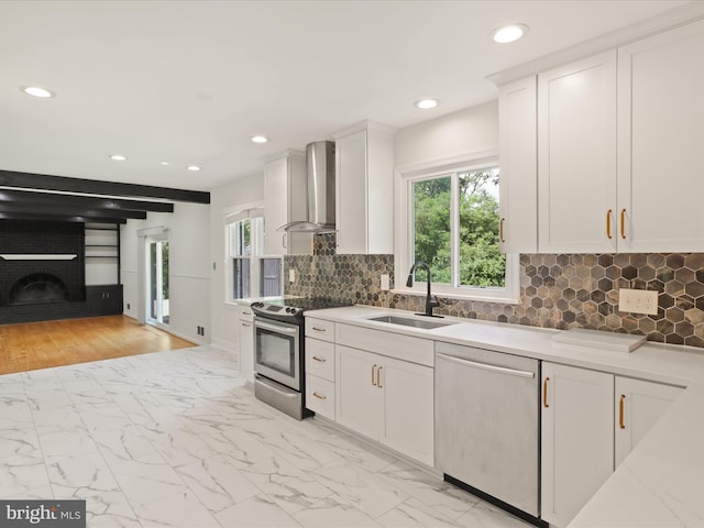 9301 Reef Ct, Alexandria, VA 22309 - kitchen with stainless steel appliances, wall chimney range hood, a sink, a brick fireplace, and recessed lighting
