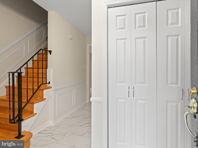 9301 Reef Ct, Alexandria, VA 22309 - stairway featuring marble look tile flooring, a decorative wall, and a wainscoted wall