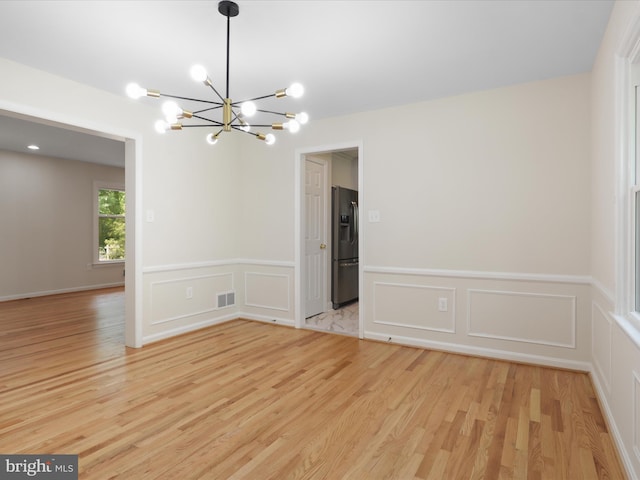 9301 Reef Ct, Alexandria, VA 22309 - unfurnished room with a chandelier, light wood finished floors, a decorative wall, and wainscoting