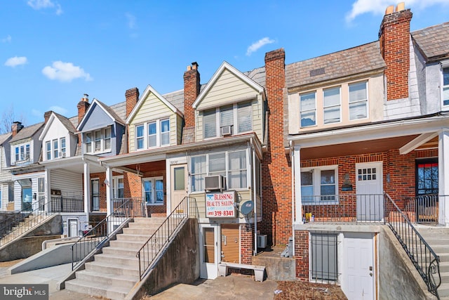 multi unit property featuring a porch, stairway, and brick siding