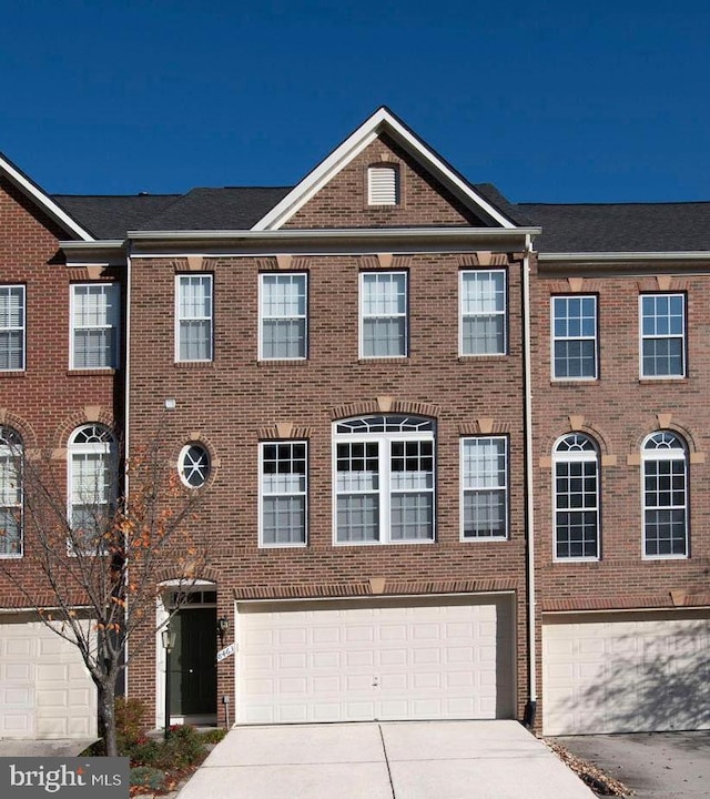 view of property with a garage, concrete driveway, and brick siding