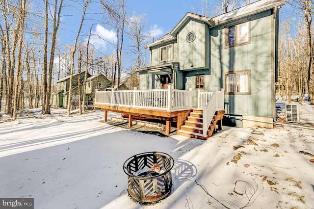 snow covered house with a wooden deck and a fire pit