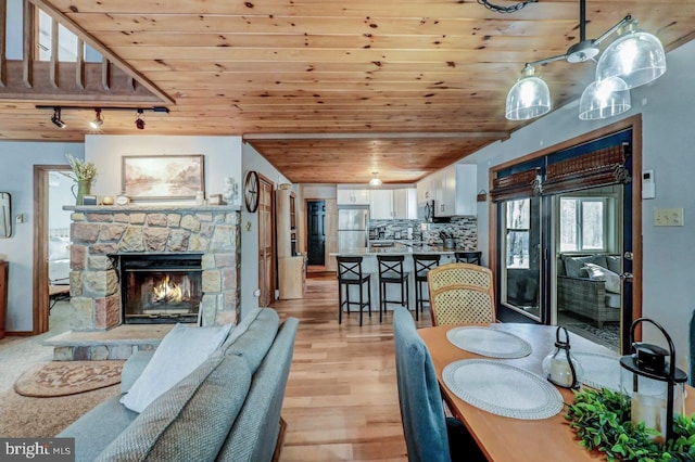 dining space featuring wood ceiling, a fireplace, light hardwood / wood-style floors, and rail lighting