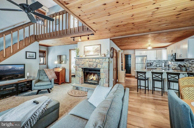 living room featuring light hardwood / wood-style flooring, ceiling fan, a fireplace, track lighting, and wooden ceiling