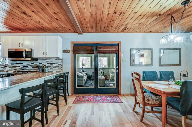 dining space featuring wood ceiling, beam ceiling, and light hardwood / wood-style floors