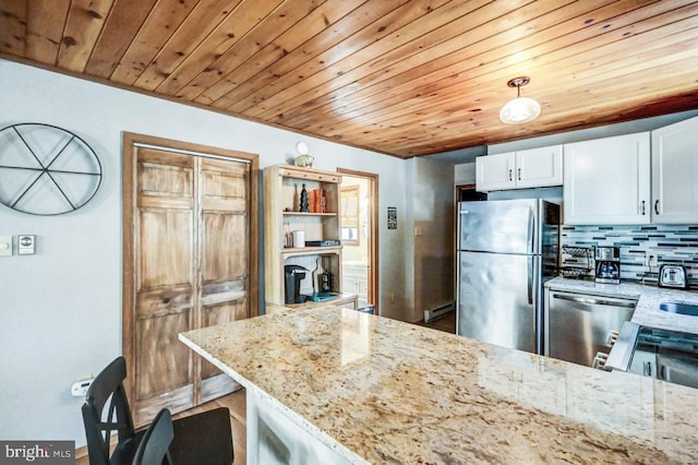 kitchen featuring light stone counters, white cabinetry, decorative light fixtures, stainless steel appliances, and decorative backsplash