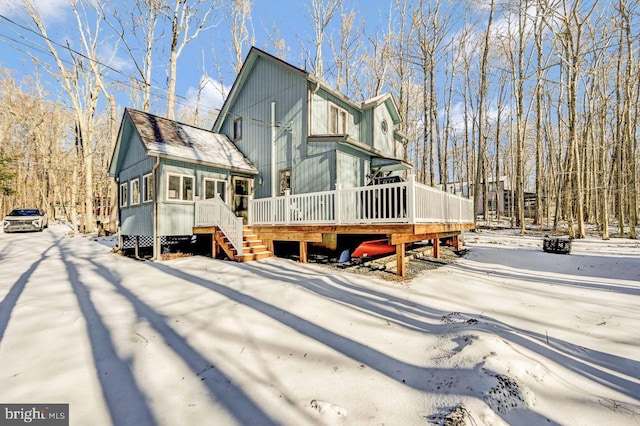 snow covered rear of property with a sunroom and a deck