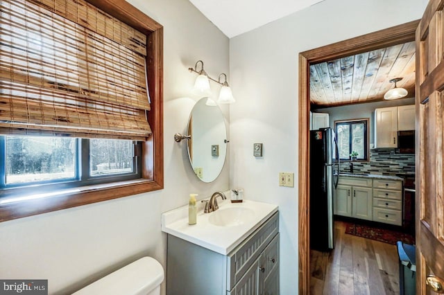 bathroom featuring toilet, tasteful backsplash, wood ceiling, wood-type flooring, and vanity