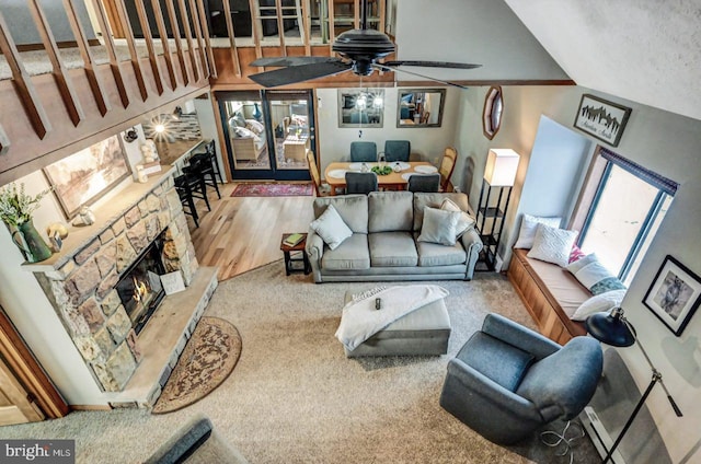 living room featuring a stone fireplace, wood-type flooring, ceiling fan, and vaulted ceiling