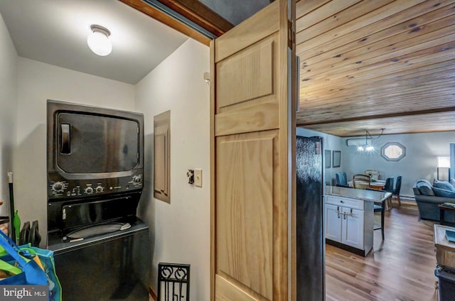 laundry area featuring hardwood / wood-style flooring, wood ceiling, stacked washer / drying machine, and a chandelier