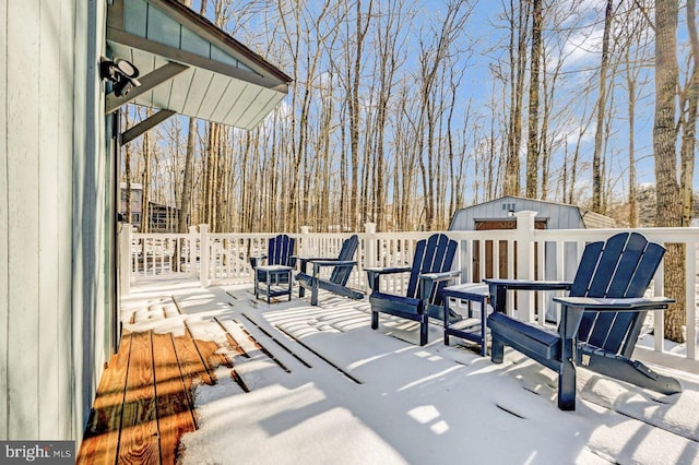 snow covered patio featuring a shed