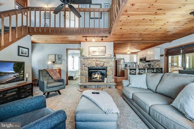 living room featuring a fireplace, carpet floors, a high ceiling, ceiling fan, and wooden ceiling