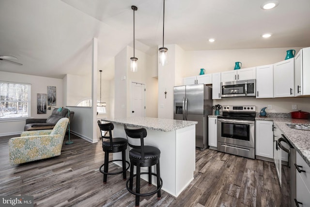 kitchen featuring a center island, hanging light fixtures, appliances with stainless steel finishes, light stone countertops, and white cabinets