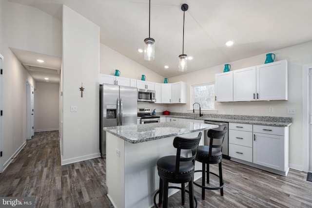 kitchen with stainless steel appliances, decorative light fixtures, a center island, and white cabinets