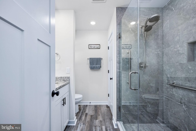 bathroom featuring vanity, hardwood / wood-style floors, an enclosed shower, and toilet