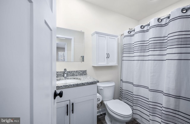 bathroom featuring vanity, curtained shower, and toilet