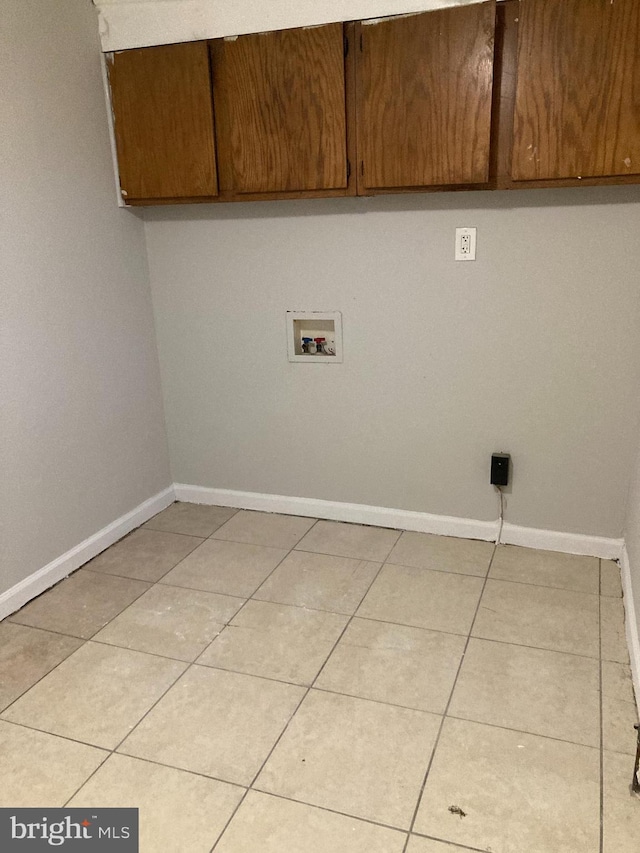 laundry area with light tile patterned flooring, cabinets, and washer hookup