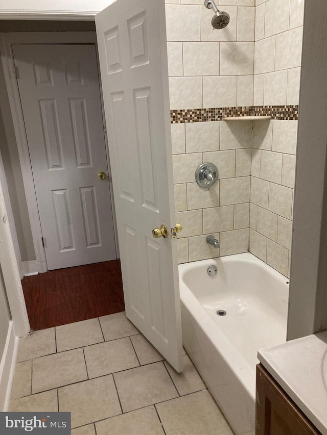 bathroom featuring tile patterned flooring, tiled shower / bath, and vanity