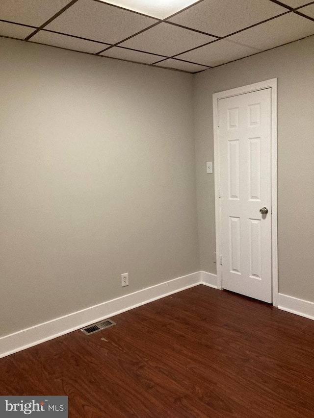 empty room featuring a paneled ceiling and dark hardwood / wood-style flooring