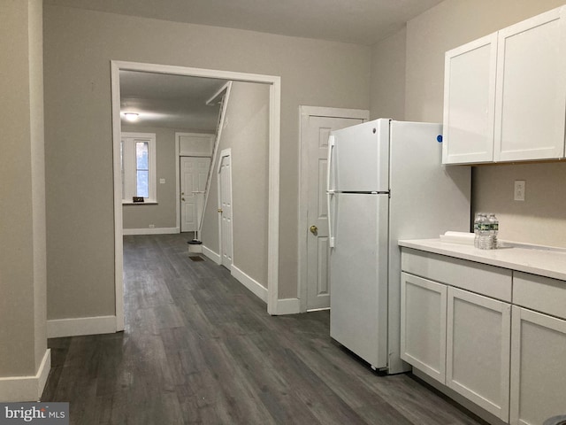 kitchen with white cabinetry, white refrigerator, and dark wood-type flooring