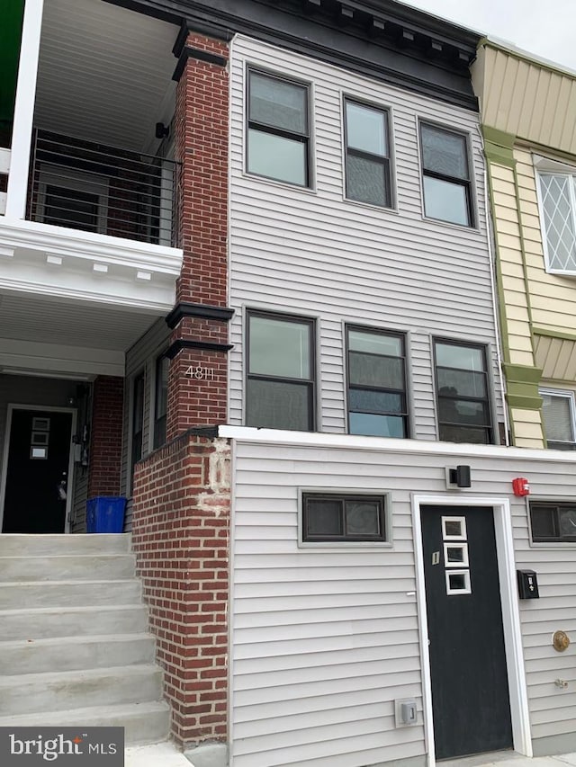 exterior space featuring brick siding and a balcony