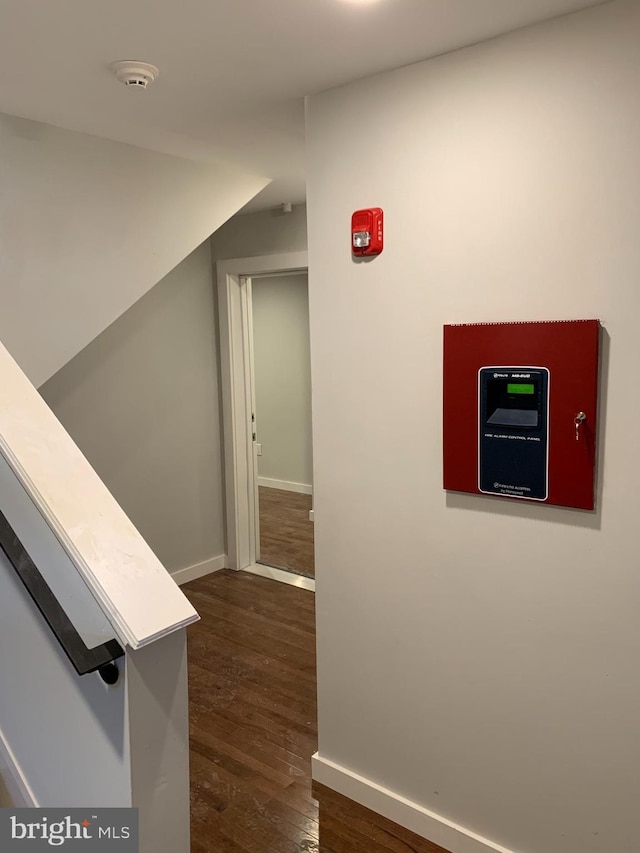 corridor with dark wood-style flooring and baseboards